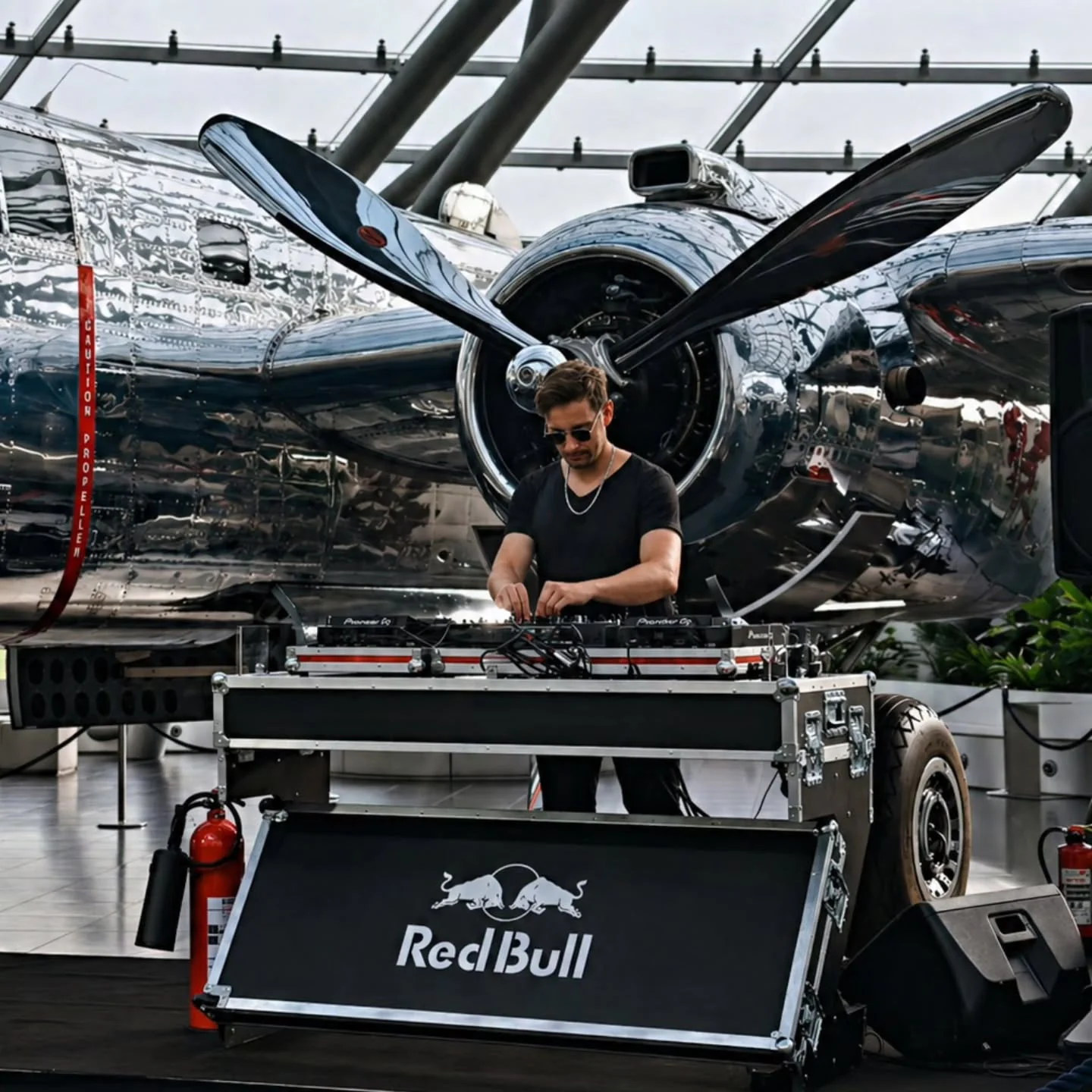 DJ Robinho bei einem Event im Hangar-7 vor einem historischen Propellerflugzeug