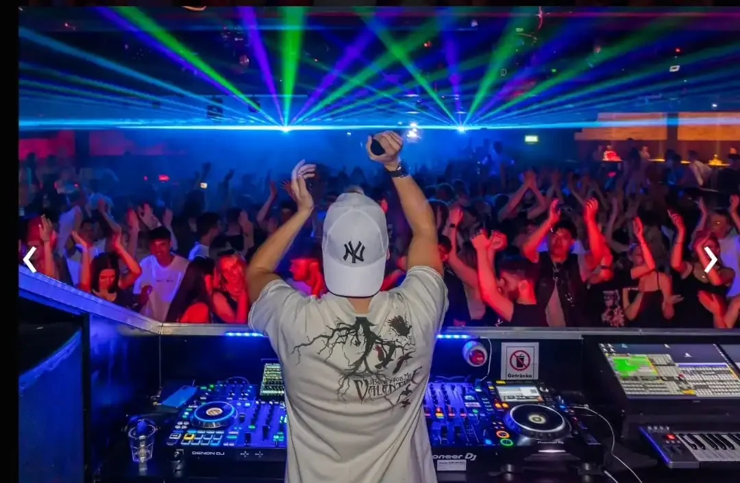 DJ Robinho am DJ-Pult vor voller Tanzfläche mit Lasershow im Club