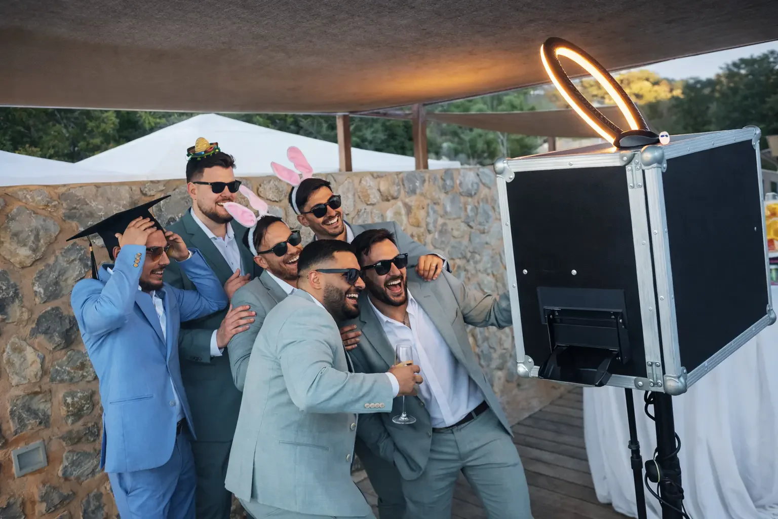 Gäste in Anzügen posieren mit Requisiten vor der Fotobox